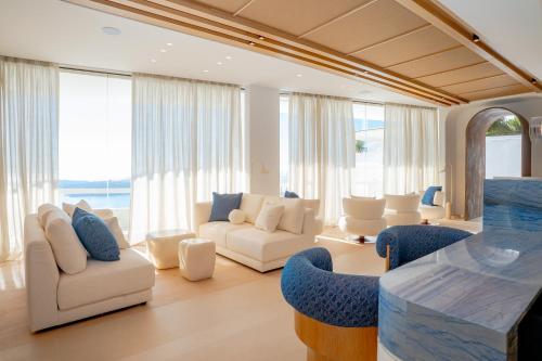 a living room with white furniture and large windows at Apeiron Blue Santorini by Apeiron Hotels in Fira