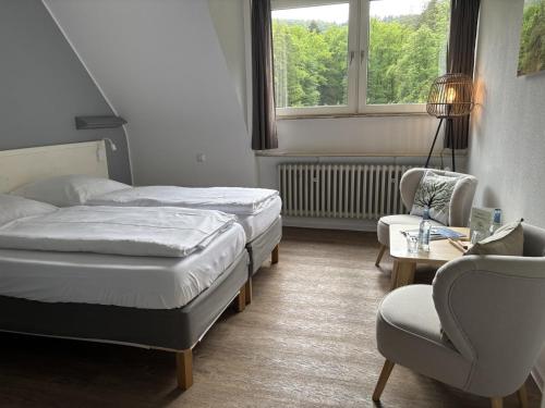a hotel room with two beds and a chair at Die Heilsbach gGmbH in Fischbach