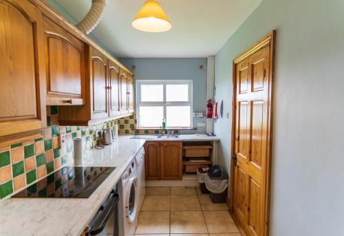 a kitchen with wooden cabinets and a sink and a window at Crab Cottage - Portmagee in Lateeve