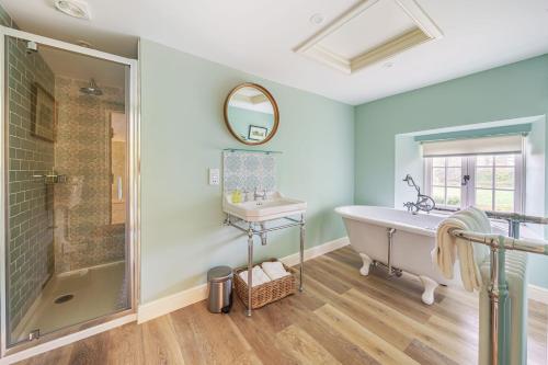 a bathroom with a tub and a sink and a mirror at Puddle Cottage in Dorchester