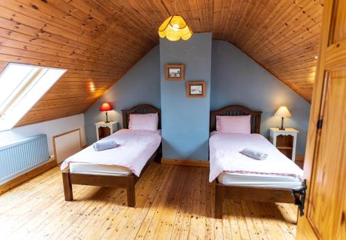 two beds in a room with a wooden ceiling at Crab Cottage - Portmagee in Lateeve