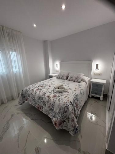 a white bedroom with a bed with a floral bedspread at Mi Capricho in Mijas Costa