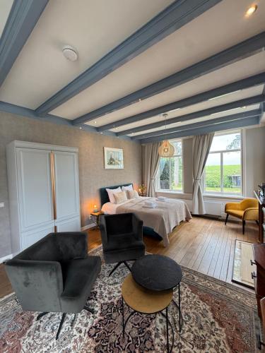 a bedroom with a bed and a couch and chairs at De Stadshoeve in Medemblik