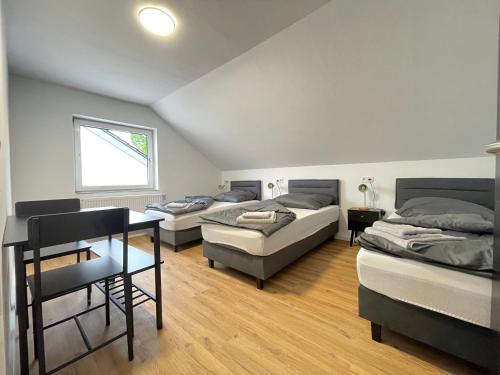 a room with three beds and a table and a window at GWP Apartments in Lohmar