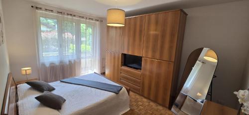 a bedroom with a bed and a cabinet and a television at Eve's Home with Garden in Magreglio
