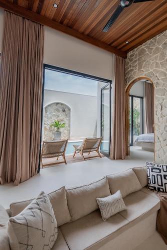 a living room with a couch and a large window at Enso Villa and Hotel in Munggu