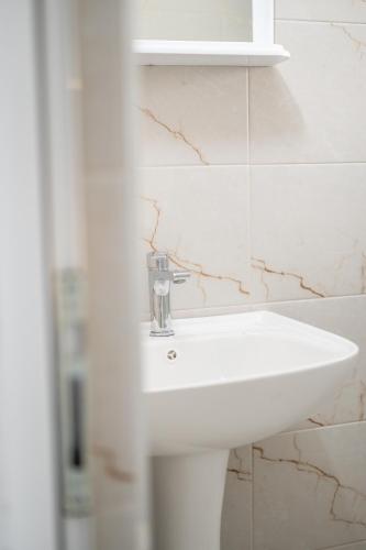 a white sink in a bathroom with marble walls at Allma Kitesurf in Donji Štoj