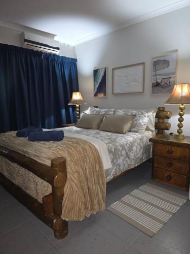 a bedroom with a large bed with blue curtains and a nightstand at CasaMari guesthouse in Pretoria