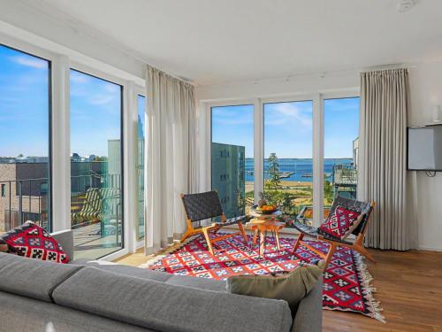 a living room with a couch and a table and windows at Apartment Penthouse Seevibes by Interhome in Lembruch