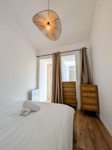 a bedroom with a white bed and a lamp at Maisonnette proche centre ville et plage in Saint-Brevin-les-Pins