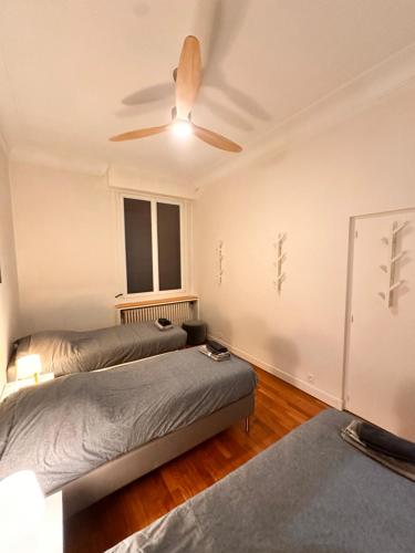 a bedroom with two beds and a ceiling fan at GRAND APPARTEMENT de 120 m2 à 5 minutes du Metro 7 lits in Les Lilas