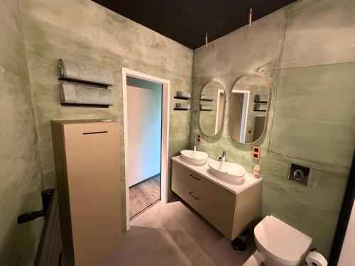 a bathroom with a sink and a toilet and two mirrors at Olivine 12 in La-Roche-en-Ardenne