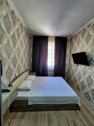 a bedroom with a bed and a tv on the wall at One-Bedroom Apartment in Fergana