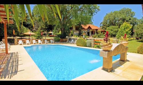 a swimming pool in a yard with chairs and a house at Blumenau Apart Hotel in Villa General Belgrano