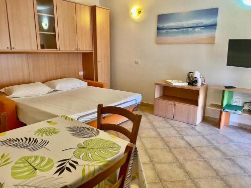 a hotel room with two beds and a table and chairs at New Orange Studio 9 in Budoni