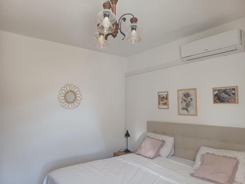 a white bedroom with a bed and a chandelier at Studio apartman Marija in Bol