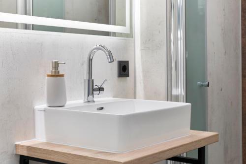 a white bathroom sink with a soap dispenser on it at Hotel Franken in Forchheim