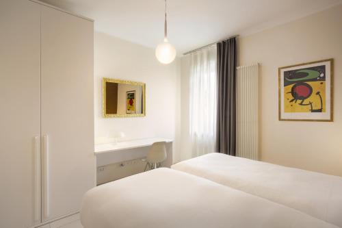 a white bedroom with two beds and a window at Cà Gardesana With Pool in Garda