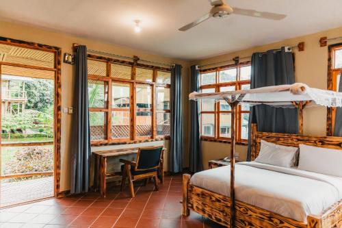 ein Schlafzimmer mit Bett, Schreibtisch und Fenstern in der Unterkunft Forest Sunset Hotel in Morogoro