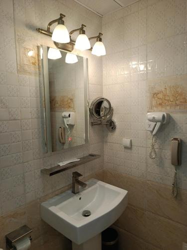 a bathroom with a sink and a mirror and a phone at Grand Hôtel City - Akwa in Douala