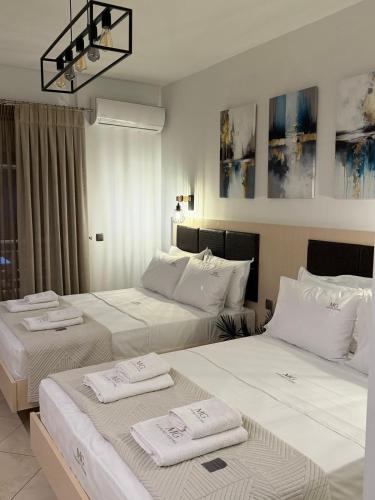 two beds in a hotel room with towels on them at MG Luxury Living in Nea Vrasna