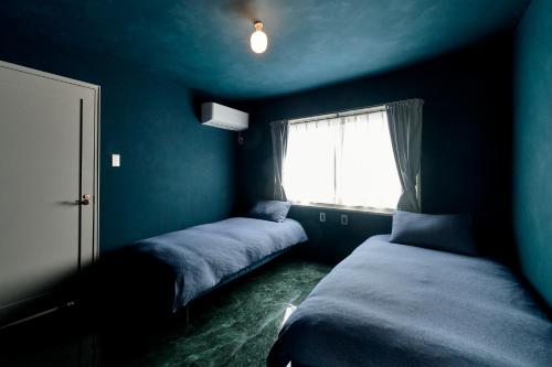 a blue room with two beds and a window at Suikomareso 2 水処稀荘 三隈川別館 in Hita