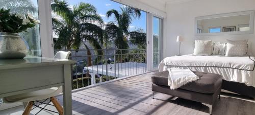 a bedroom with a bed and a balcony with palm trees at Strode House in Knysna