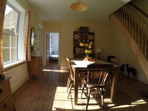 a dining room with a table and chairs and a staircase at Pinecroft B&B in Lymington