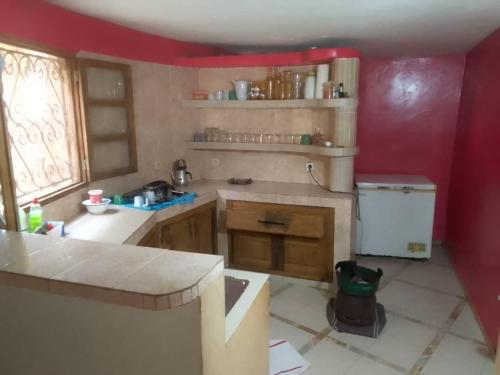 a kitchen with red walls and a sink and a counter at Ecolodge EcoFarm Fimela in Fimela