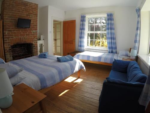 a bedroom with two beds and a couch and a fireplace at Pinecroft B&B in Lymington