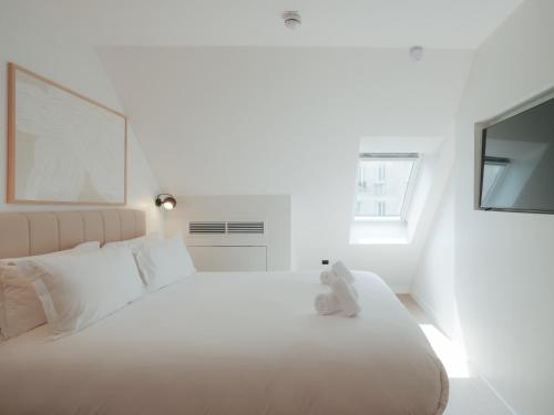 a white bed with a teddy bear sitting on it at City Pop 2Night Paris - Self check-in in Vanves