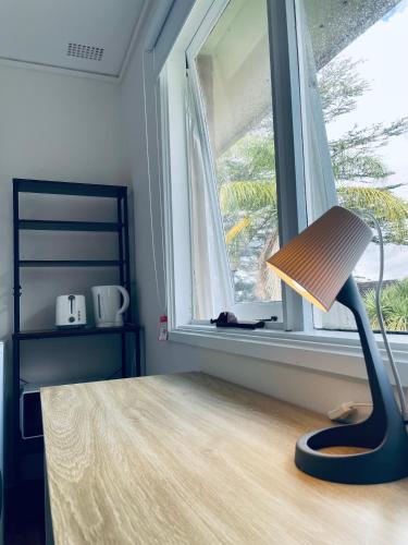 a lamp sitting on a table in front of a window at Coral House in Sydney