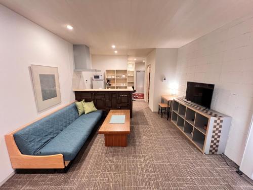 a living room with a blue couch and a kitchen at 内町2階 1フロアまるごと貸切 高松中心部 4名まで in Takamatsu