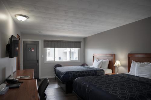 a hotel room with two beds and a desk at Aquarius Motel in Perth