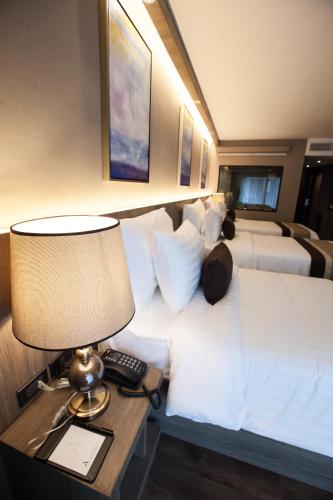 a hotel room with two beds and a table with a lamp at Arte Hotel - SHA Extra Plus in Bangkok