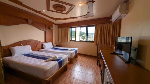 a hotel room with two beds and a television at Tiger Complex Hotel and Restaurant in Patong Beach