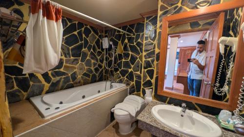 a man taking a picture of a bathroom with a tub and sink at Tiger Complex Hotel and Restaurant in Patong Beach