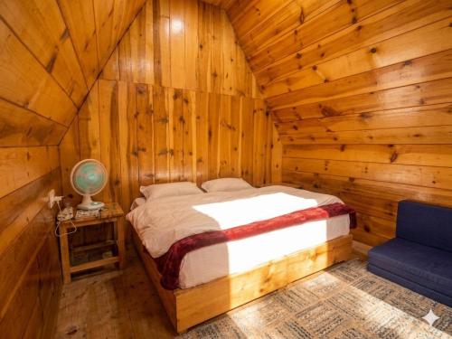 a bedroom with a bed in a log cabin at Hima 360, A Frame Cabin, Panaromic Sainj Valley Views, Bhatkanda in Sainj