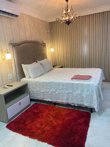 a bedroom with a large bed with a red rug at Hotel Tauari in Marabá