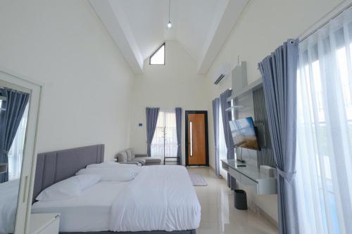 a white bedroom with a large bed and a television at Abata Villa Panorama & Pool in Tingkirtengah