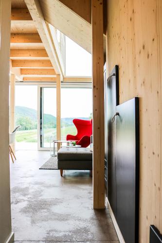 a living room with a couch and a red chair at Mosel Chalets - Design-Ferienhäuser - Terrasse und Traumblick, nähe Cochem - Direkt am Weinberg, Chalet Mitte mit Sauna in Pommern