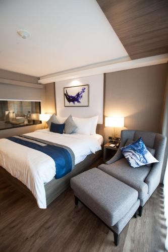 a hotel room with a bed and a chair at Arte Hotel - SHA Extra Plus in Bangkok