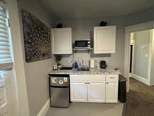 a kitchen with white cabinets and a sink and a dishwasher at Downtown Lake Eola Historic House 1 OR 2 BED in Orlando