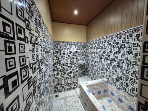 a bathroom with a tiled wall with a tub at Muka House in Ubud