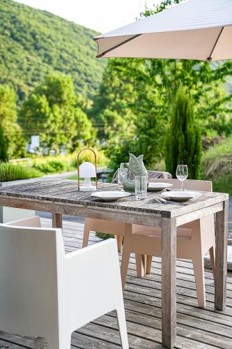 a wooden table with white chairs and an umbrella at Mosel Chalets - Design-Ferienhäuser - Terrasse und Traumblick, nähe Cochem - Direkt am Weinberg, Chalet Mitte mit Sauna in Pommern