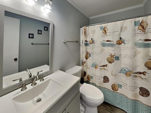 a bathroom with a sink and a toilet and a shower curtain at Lighthouse Point 3B in Tybee Island