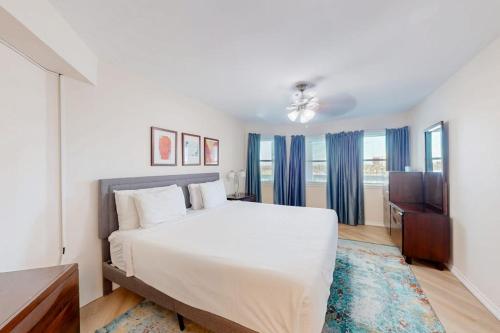 a white bedroom with a large bed and a television at Gulf Point Condominiums in South Padre Island