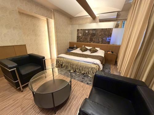 a bedroom with a bed and a couch and a chair at Hotel Orchid (Adult only) in Kurashiki
