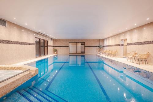 a large swimming pool with blue water in a building at Best Western Plus The Connaught Hotel and Spa in Bournemouth