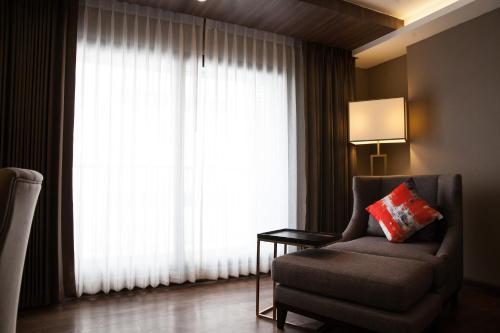 a living room with a chair and a large window at Arte Hotel - SHA Extra Plus in Bangkok